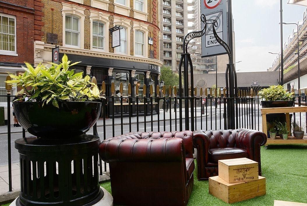 Montcalm Brewery Townhouse Ξενοδοχείο Λονδίνο Εξωτερικό φωτογραφία The photo shows a street scene with a cozy outdoor seating area. There are two plush, dark leather couches arranged on green grass, creating a welcoming atmosphere. Surrounding the seating are large planters with vibrant plants. In the background, th