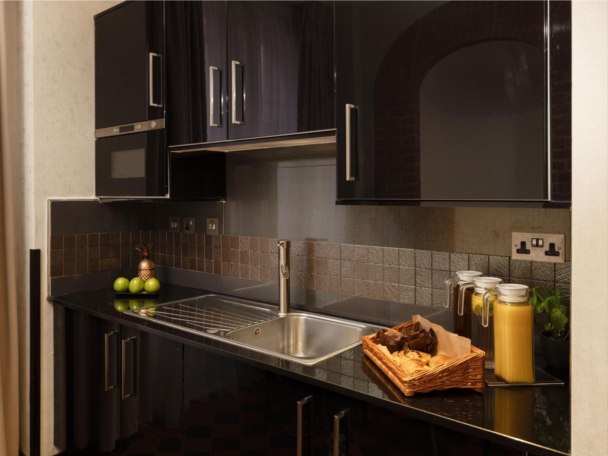Montcalm Brewery Townhouse Ξενοδοχείο Λονδίνο Εξωτερικό φωτογραφία The photo shows a modern kitchen with sleek black cabinetry and a glossy finish. The kitchen features a stainless steel sink with a contemporary faucet, set against a dark, textured countertop. Above the counter, there are cabinets that match the cou