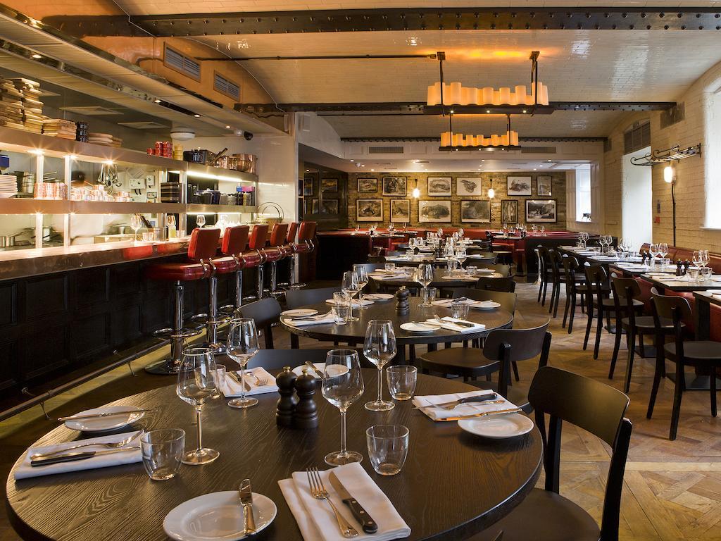 Montcalm Brewery Townhouse Ξενοδοχείο Λονδίνο Εξωτερικό φωτογραφία The photo shows the interior of a stylish restaurant. It features several round tables set with white plates, glasses, and silverware, all neatly arranged for dining. The decor includes a modern design with wooden floors and a mix of lighting fixture