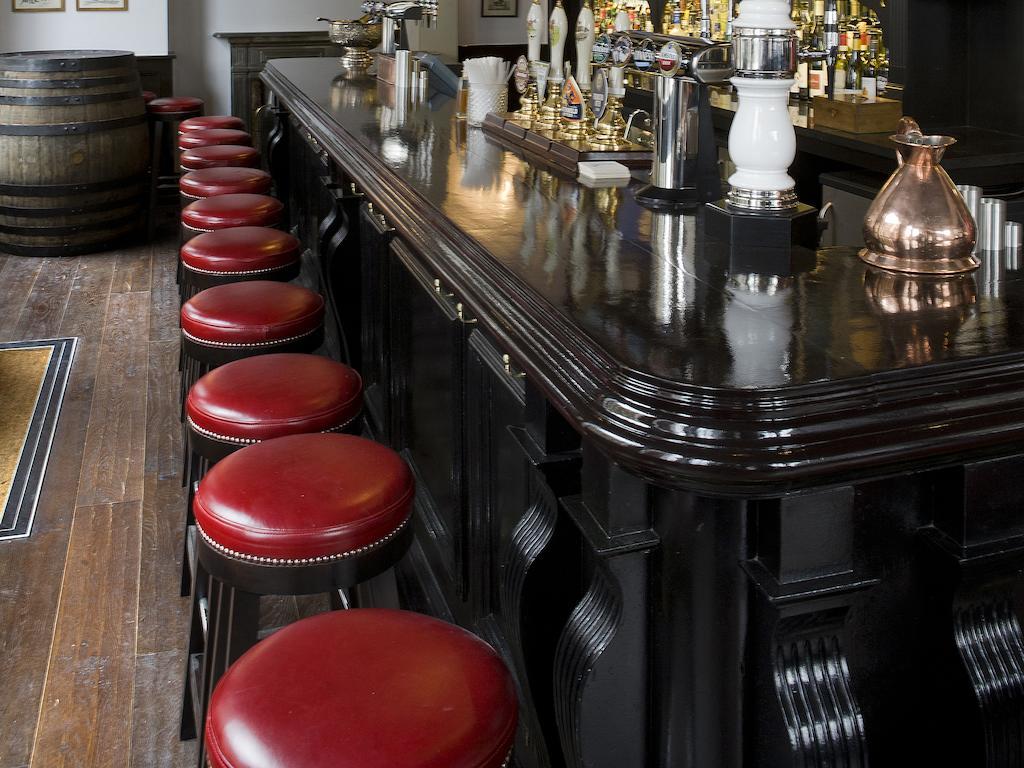 Montcalm Brewery Townhouse Ξενοδοχείο Λονδίνο Εξωτερικό φωτογραφία The photo shows a bar setting with a long, polished dark wooden bar counter. Attached to the counter are several bar stools with red leather seats. Behind the bar, there are various bottles, suggesting a well-stocked bar. The flooring appears to be w